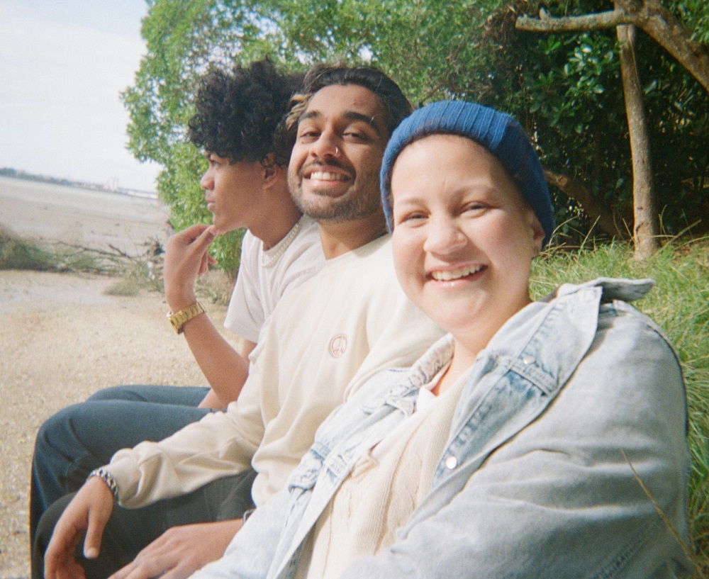 young person in a wheel chair with two friends on a walk in the park